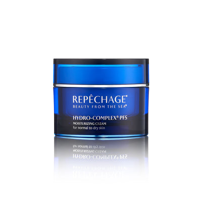 A jar of REPECHAGE Hydro-Complex PFS Moisturizing Cream for dry skin, with blue and white labeling, placed on a reflective surface.
