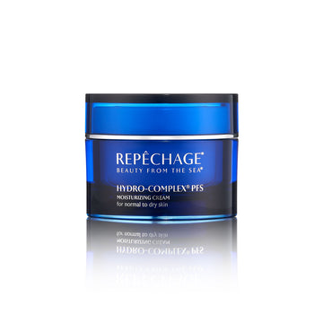 A jar of REPECHAGE Hydro-Complex PFS Moisturizing Cream for dry skin, with blue and white labeling, placed on a reflective surface.