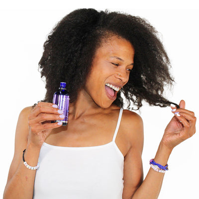 Woman holding Hydra-Amino 18 Hair Spa Serum bottle and looking at hair