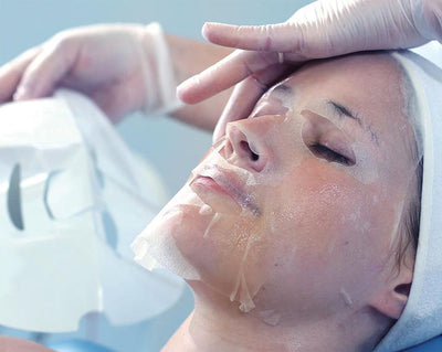 Woman laying down wearing Red-Out® Soothing Sheet Mask