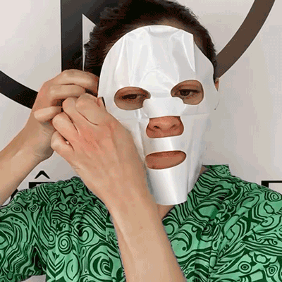 woman applying red out sheet mask to face